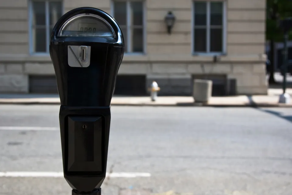 Close-up of black parking meter with blurred street in background